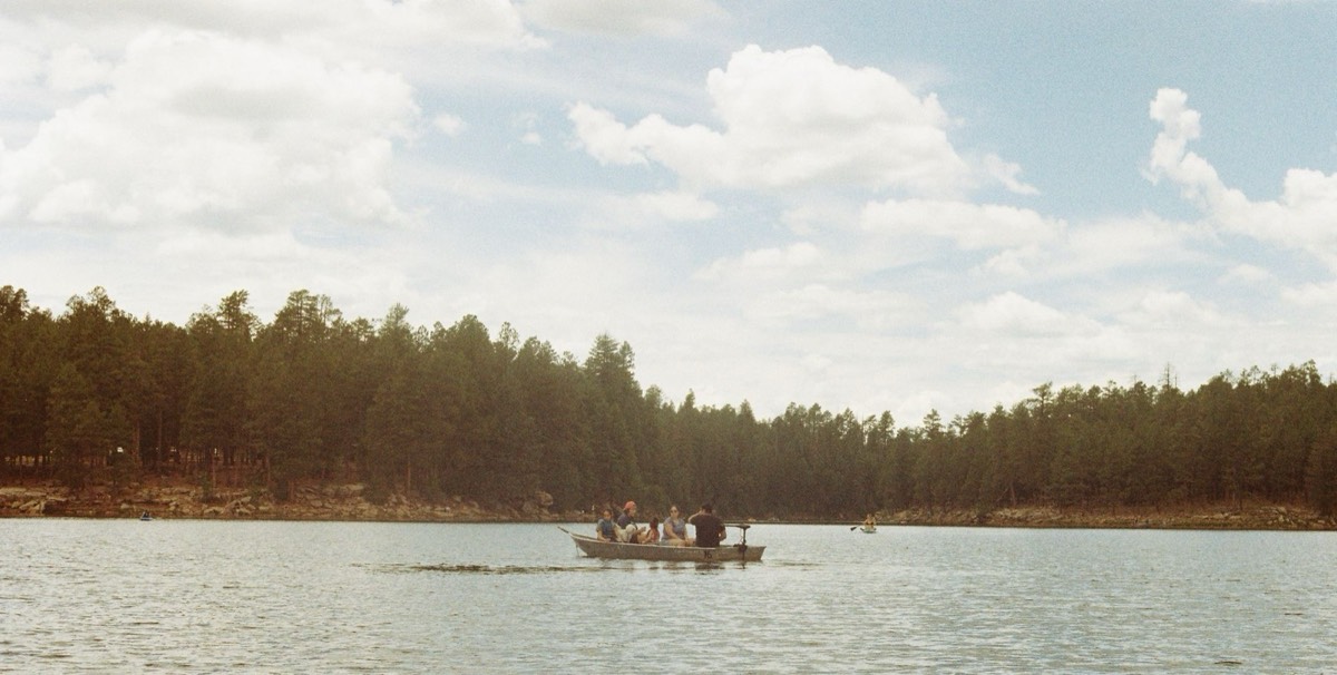 Boaters on a pine-ringed Arizona mountain lake, similar to Show Low Lake and Big Lake near Pinetop